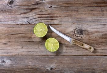 Sliced lime and paring knife on rustic wood in flat lay format