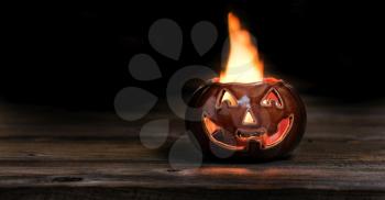 Fiery Halloween pumpkin on wood at night