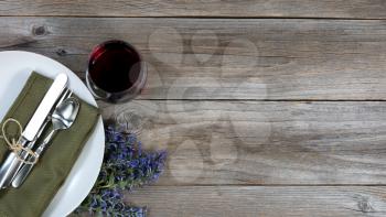 Vintage table setting with fresh flowers and a glass of red wine on rustic wood