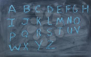 Alphabet letters written with blue chalk on clean blackboard