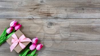 Gift box with pink tulips on rustic wooden boards for Mothers day Background 