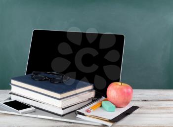Back to school concept consisting of technology and traditional stationery with green chalkboard 