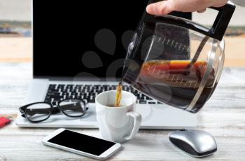 Close up of male hand pouring fresh coffee with workstation technology in background for business or education use 
