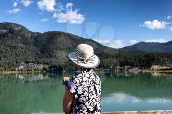 Portrait of senior woman looking out to lake with back to camera 