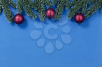 Merry Christmas holiday top border with fir and red ball ornaments on blue background for the season  
