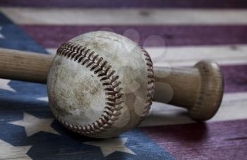 Closeup view of an old baseball and traditional wood bat on rustic wooden United States Flag
