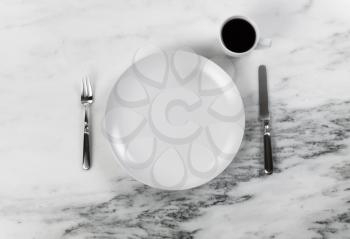 Coffee drink plus dinner setting with clean plate, knife and fork on marble table  