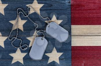 Close up view of military ID tags for Memorial, 4th of July and Veterans Day holiday on rustic US wooden flag background 