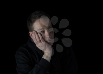 Depressed mature man holding his cheek in the darkness while looking sad  