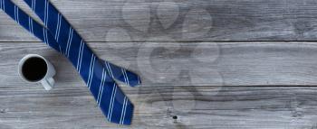 Blue striped necktie and a cup of coffee on aged wooden desk for Happy Fathers Day concept