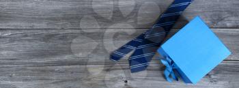 Blue striped necktie and a gift box on weathered wooden planks for Happy Fathers Day concept 