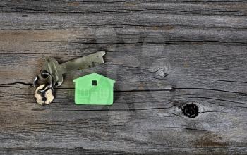 Close up of miniature house key holder with antique key on vintage wooden plank background 