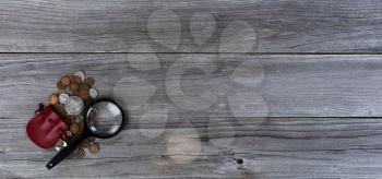 Collection of vintage coins with pouch and magnifying glass on weathered wooden planks 