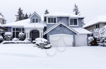 Curbside view of residential home during winter snowstorm with visual light snow coming down 