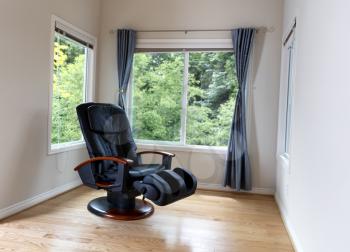 Home massage chair near large windows with view of trees in full bloom 