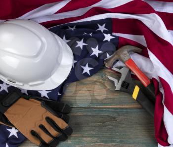 Happy Labor Day concept background with American flag and construction work equipment on faded blue wood 