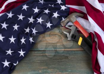 Happy Labor Day concept background with American flag and construction work tools on faded blue wood 