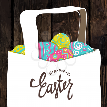 Basket with Easter colorful eggs. Happy Easter calligraphy. Wooden board background. Easter postcard.