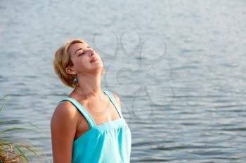 portrait of a young woman closed her eyes from the evening sun on the background of sea water
