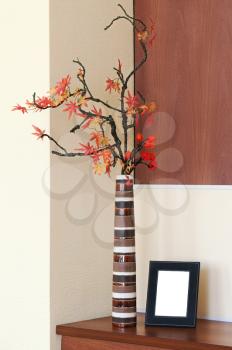 Autumn arrangement in a vase on the table and photoframe with place for your foto.