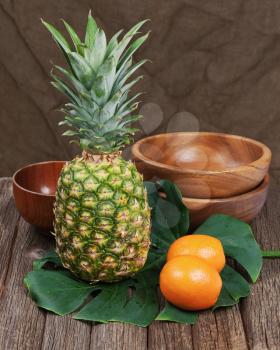 Still life with pineapple and oranges on wooden table. Closeup.