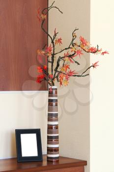 Autumn arrangement in a vase on the table and photoframe with place for your foto.