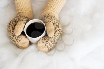 Woman hands in teal gloves are holding a mug with hot coffee or cocoa.  Winter and Christmas concept.
