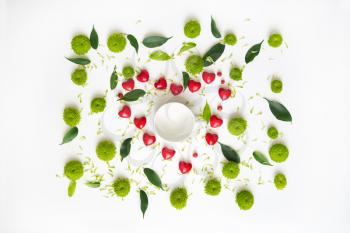 Cup for coffee or tea with pattern with petals of chrysanthemum flowers, ficus leaves, hearts and ripe rowan on white background. Overhead view. Flat lay.
