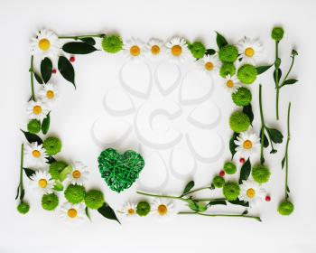 Heart with pattern from petals of chrysanthemum flowers, ficus leaves and ripe rowan on white background. Overhead view. Flat lay.