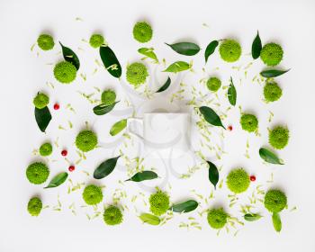 Cup for coffee or tea with pattern from petals of chrysanthemum flowers, ficus leaves and ripe rowan on white background. Overhead view. Flat lay.
