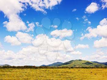 Landscape with mountain views, arable land, blue sky and beautiful clouds. Real scene without any light effects.
