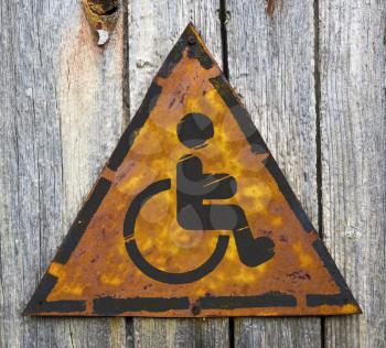 Royalty Free Photo of a Rusty Metal Handicapped Sign on a Wood Wall