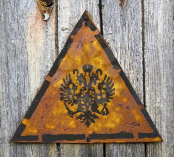 Double Eagle - Russian Coat of Arms on Weathered Triangular Yellow Warning Sign. Grange Background.