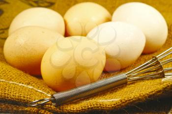 Macro shot of several eggs with a whisk on a table hessian cloth