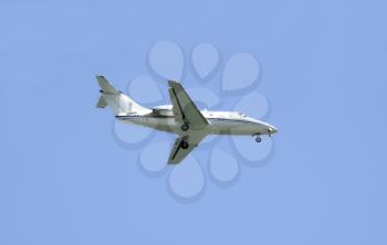 Modern private jet over a bright blue sky getting ready to land 