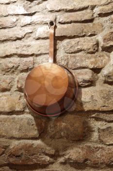 antique copper cookware on a brick wall