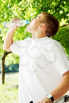 Young boy on a bike drinking water