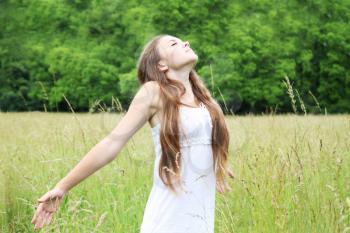 Free young woman on the meadow breathes in deeply