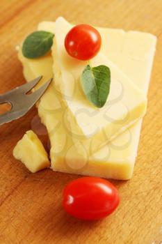piece of cheese with small tomatoes on a wooden board