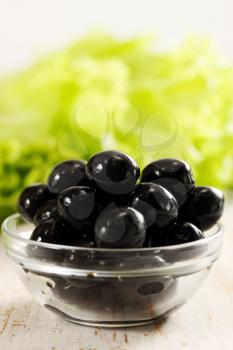 Black olives in a bowl transparent and lettuce