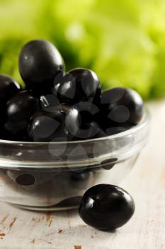 Black olives in a bowl transparent and lettuce