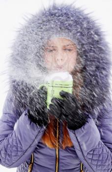 Woman blowing on a cup full of snow
