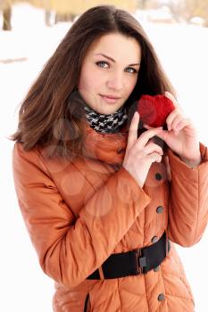 Young woman holding a red heart in the hands of