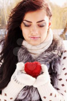 Young woman holding a red heart in the hands of