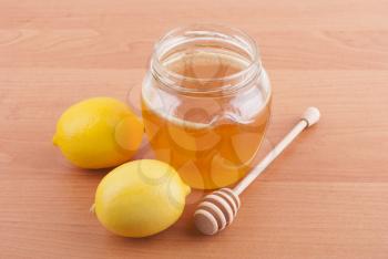 Fresh honey in a glass jar and lemons.