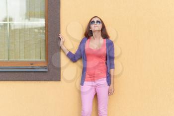 Young stylish woman posing against the wall.