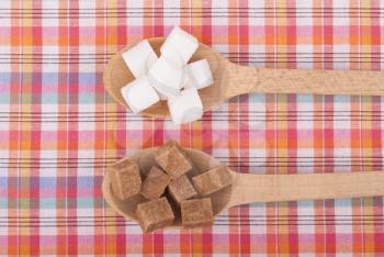 Refined sugar in the spoons on the table cloth.