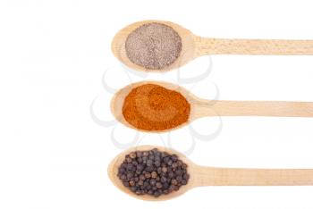 Spices on wooden spoons isolated on white background.