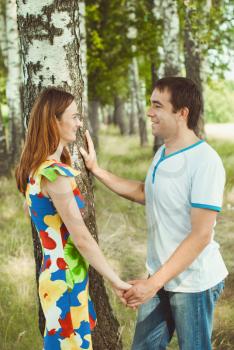 Young happy couple holding hands in the park in the summer.