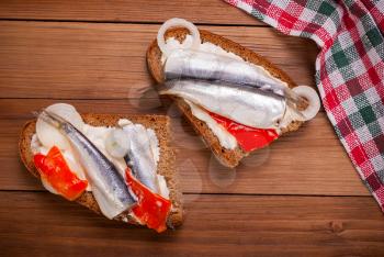 Sandwich with a sprat on a wooden background .